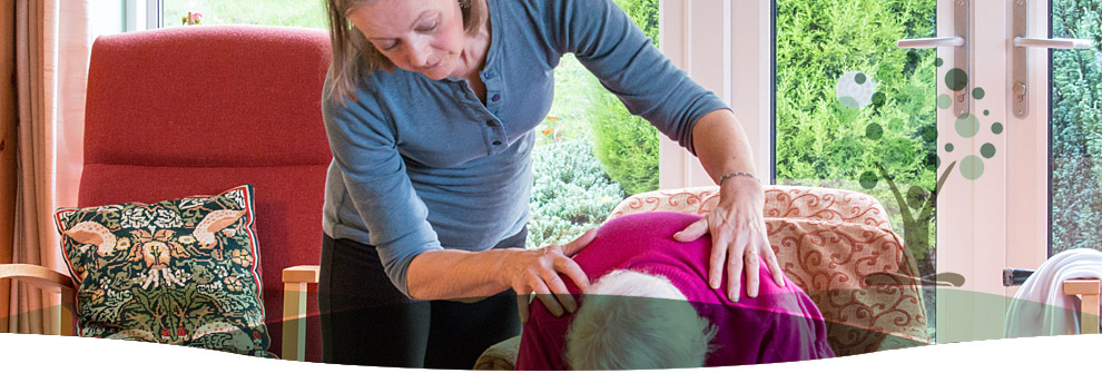 Sarah adjusting a student resting forward on a bolster